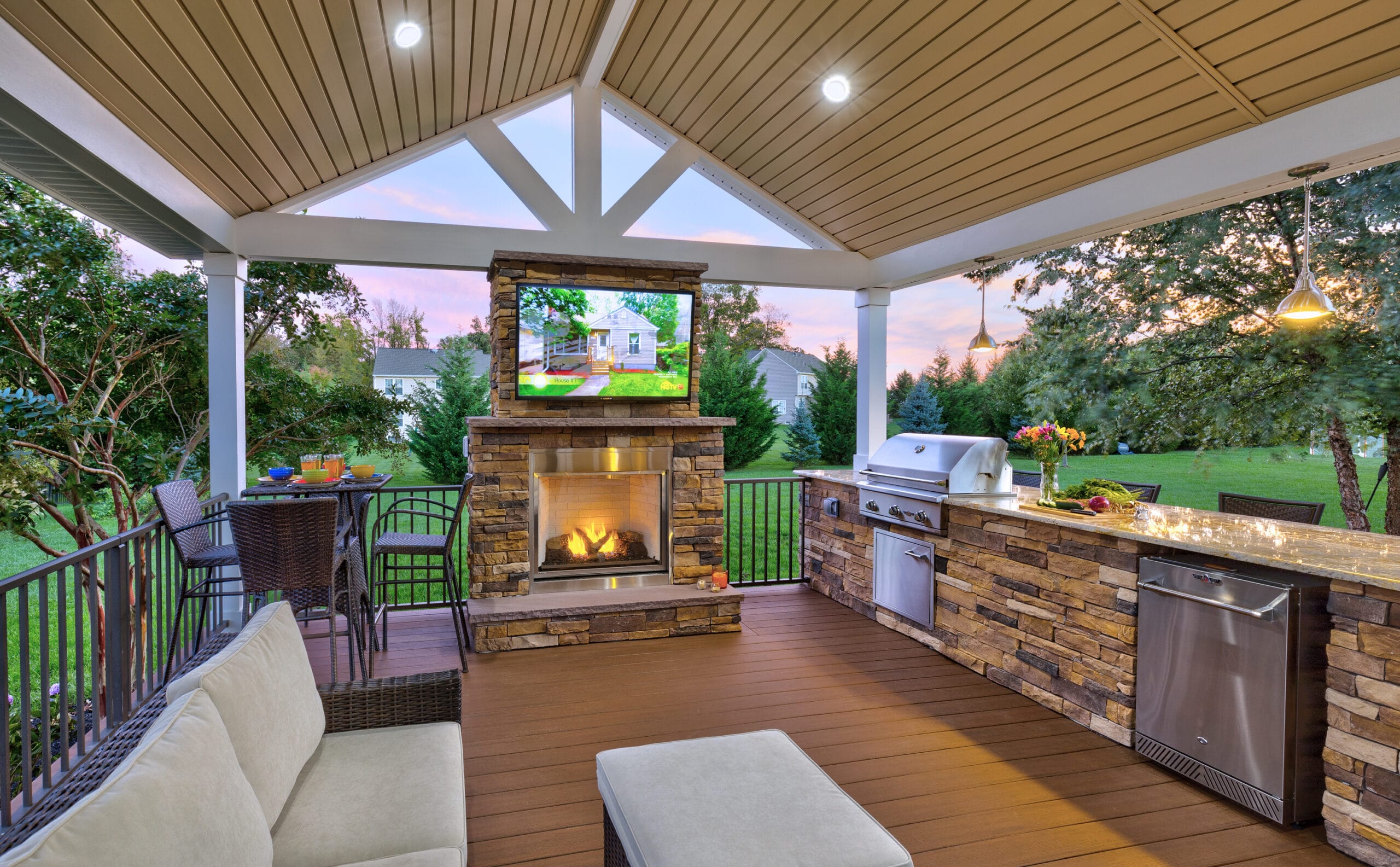 Luxury outdoor space equipped with appliances, sofa, television, and fireplace.