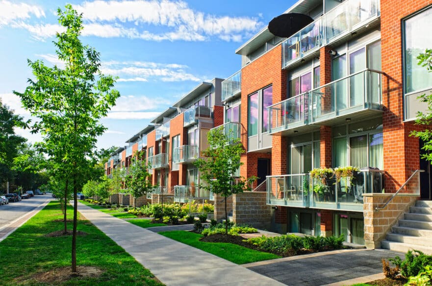 Townhouses sit in a line on a quiet street.