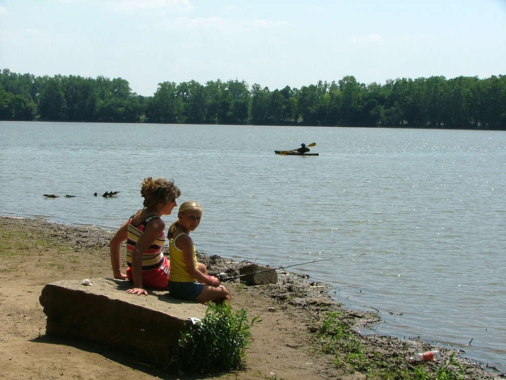 Two people fishing on the bank of Huffman Lake in Huffman MetroPark.