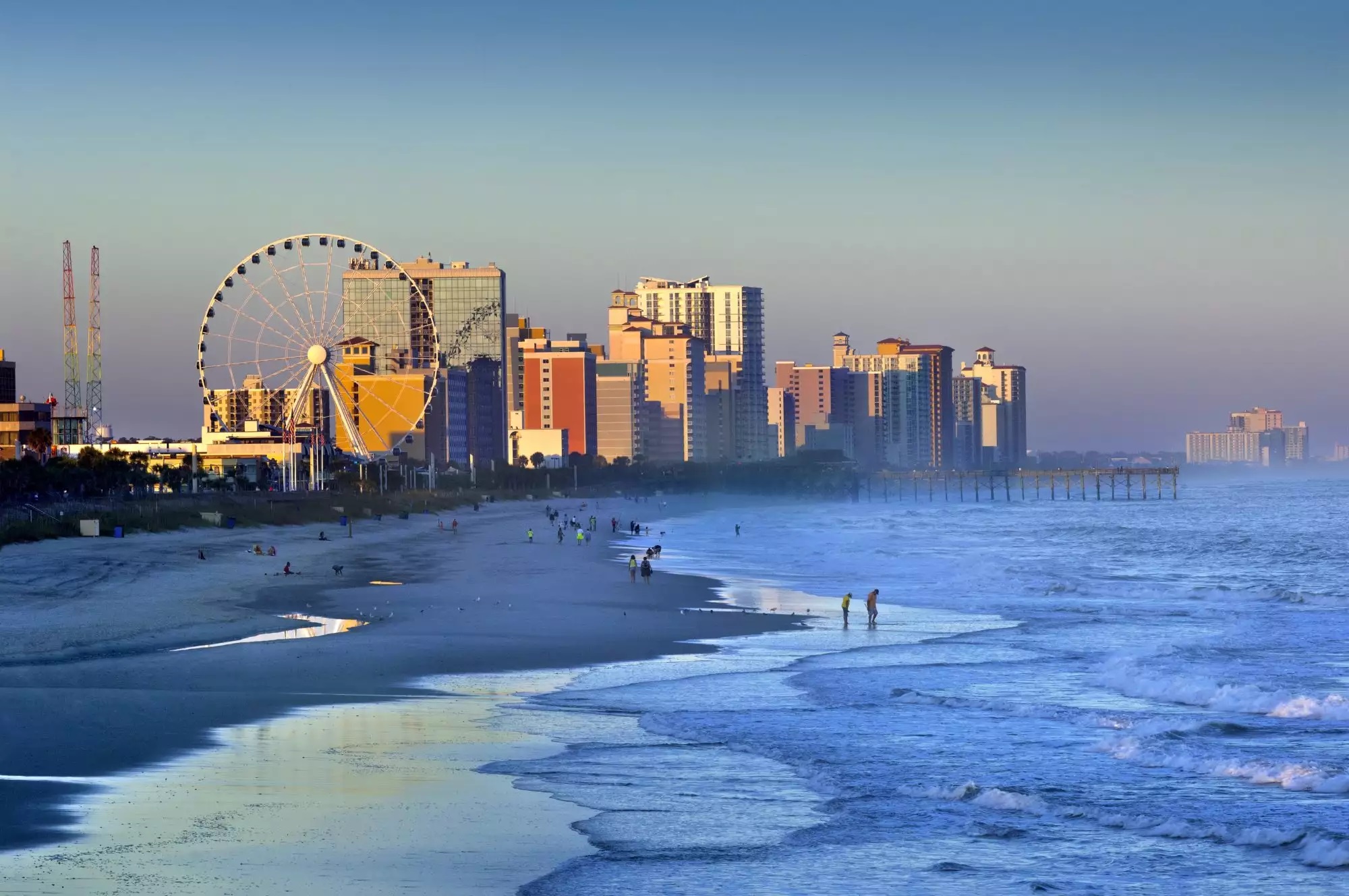 Myrtle Beach oceanfront at dusk, with the boardwalk ferris wheel in the background.