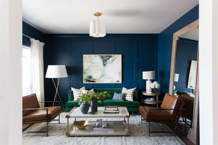 Navy blue living room walls accented by emerald green and tan furniture.