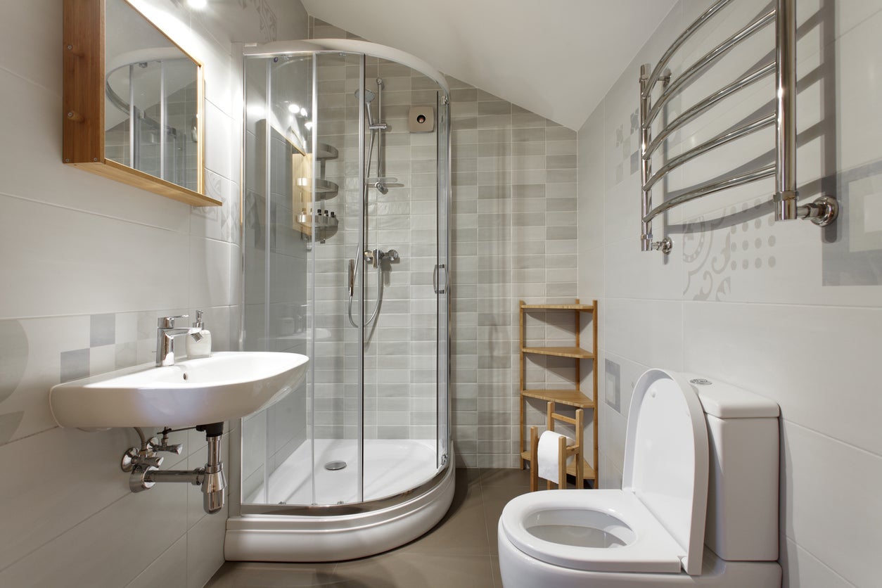 Small ¾ bathroom with stand-up shower and small sink and toilet.