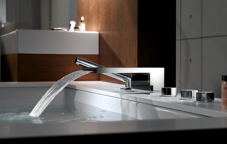 Modern silver plumbing fixtures filling a large white bathtub.