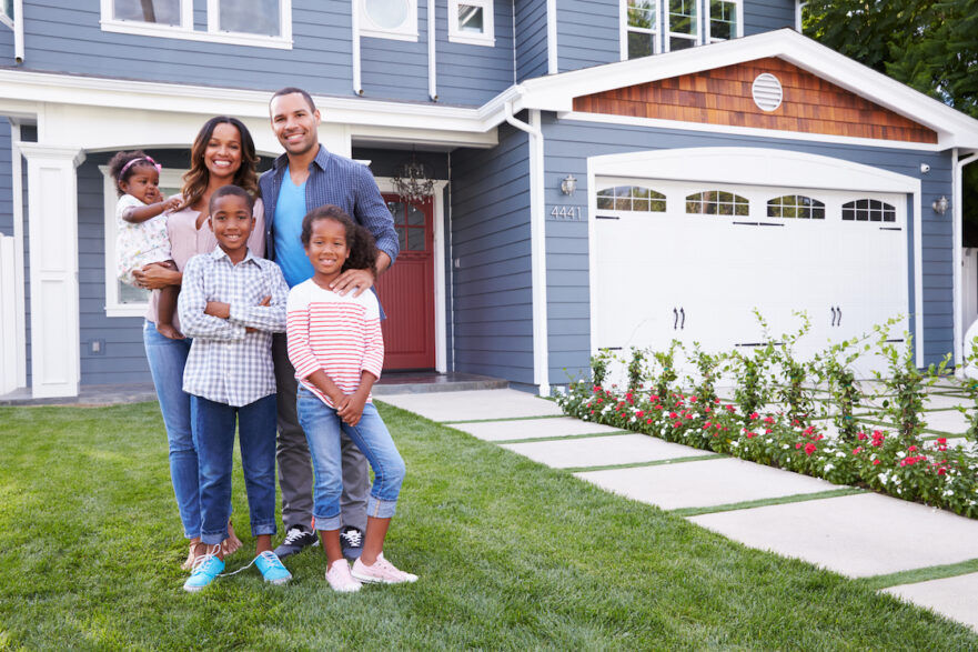 Happy family standing outside of their new custom home.