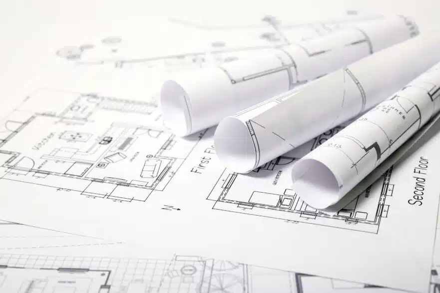Three rolled-up architectural plans on top of a design for a two-story new home.