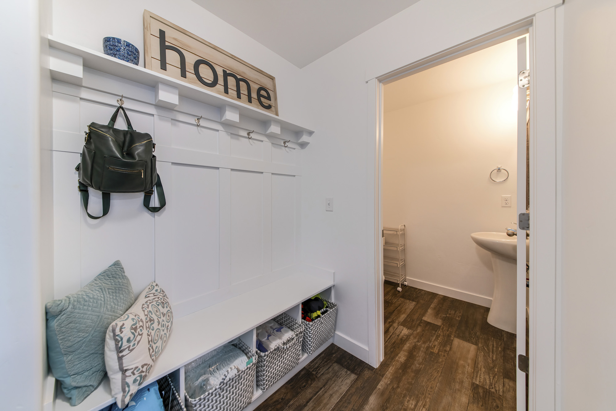 A white-painted mudroom floor plan with a sink, bench, baskets, all hooks, and shelves.