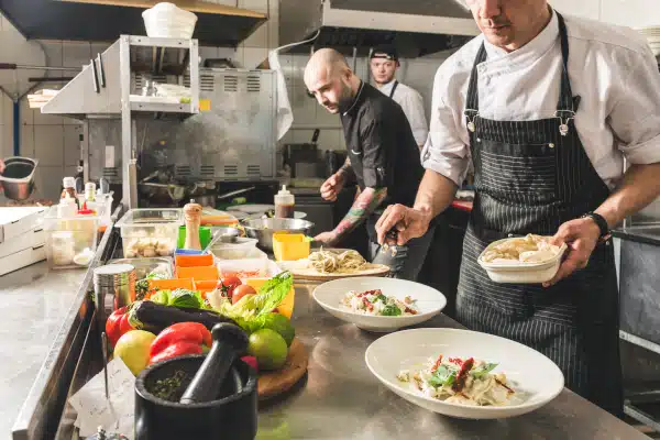 Professional chef cooking in the kitchen restaurant at the hotel, preparing dinner. A cook in an apron makes a salad of vegetables and pizza