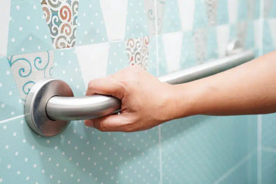 A home resident holding on to a handrail in their restroom.